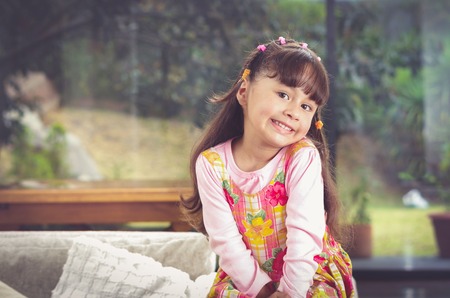 Beautiful young hispanic girl with pink clothing smiling cute at camera with blurry garden background.の写真素材