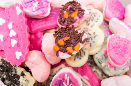 Closeup of delicious pile with cookies mostly pink colored frosting and some chocolate sprinkles.