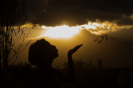 Teenage girl posing with sunset behind clouds in background creating spectacular colors, silhouette concept.の写真素材