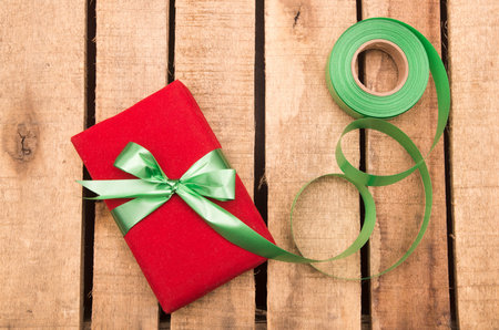 Nicely wrapped presents in red and green wrapping on wooden surface.