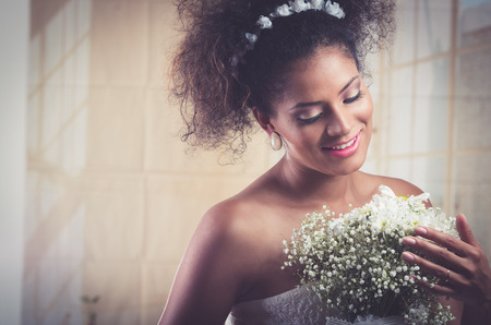 Portrait of beautiful exotic latin bride wearing white dress and holding flower bouquetの写真素材