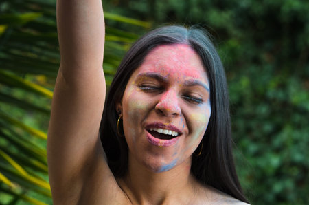 Pretty smiling latin girl having fun celebrating with painted face outdoorsの写真素材