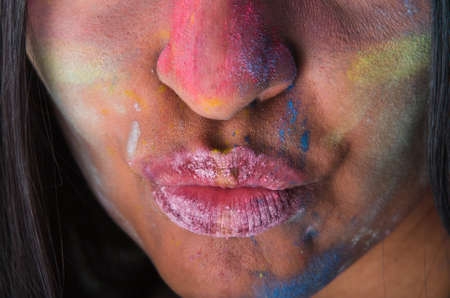 Mysterious young latin girl with colored powder on her face sending a kissの写真素材