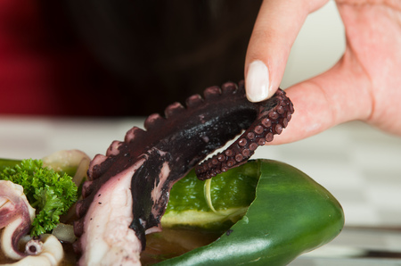 Close up shot of young woman eating delicious exotic octopus with her handsの写真素材