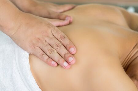 Closeup womans upper back with hands working on giving massage, spa treatment concept.の写真素材