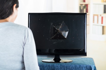 Brunette female with back to camera facing broken computer screen.の写真素材