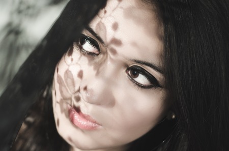 Headshot brunette model experimenting with shadows on obscure background, artistic dark beauty photo.の写真素材