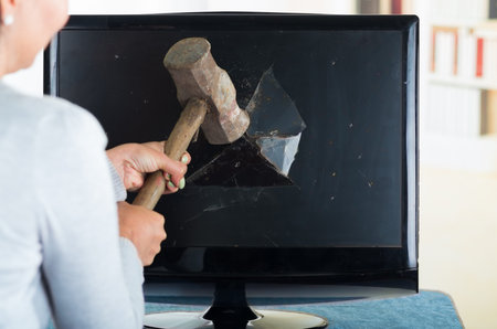 Female holding hammer smashing it into computer screen.