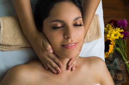 Hispanic brunette model getting massage spa treatment, hands working on massaging womans head and face with eyes closed.の写真素材