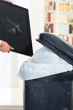 Broken computer screen going into large black trash binの写真素材