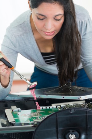 Hands working with electronic circuit board from broken computer screen using small screwdriver.の写真素材