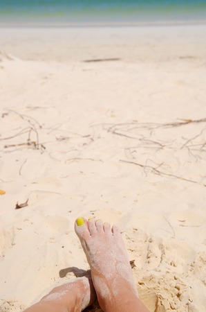 Feet crossing over each other covered in sand on Galapagos Islands beach.の写真素材