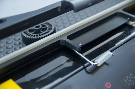 Closeup black print screen machine showing mechanical details in process.