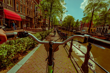 Amsterdam, Netherlands - July 10, 2015: Bikers point of view as bicycling through city streets, beautiful sumer day with water channel on right side.のeditorial素材