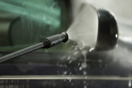 Closeup high pressure water cleaner as seen spraying on car side mirror and window.の写真素材