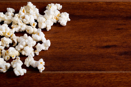 Closeup pile of white fluffy popcorn lying mixed together on wooden surface.の写真素材