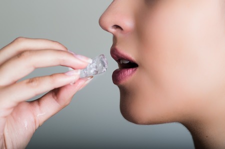 Pretty model profile angle sensually touching lips with ice cube.の写真素材