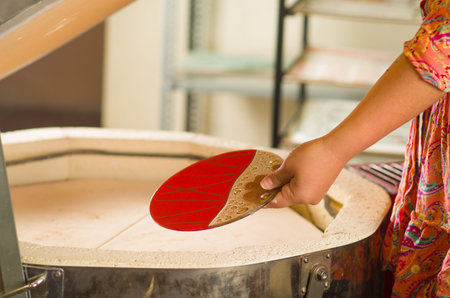 Hand holding red and trasnaprent plate with nice golden decorative stripes on it.の写真素材