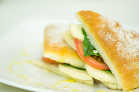 Delicious cheese, albahaca basil and tomato ciabatta sandwich on white plate.の写真素材