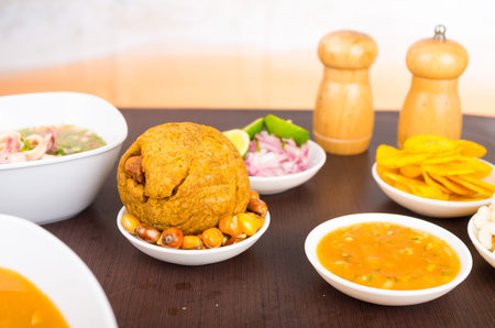 Traditional ecuadorian food, selective focus on bolon and fried corn with spicy sauce on a wooden tableの写真素材