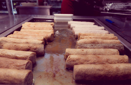 Delicious fried rolled dough, various of these on a metal  iron grilled with filter, sepia