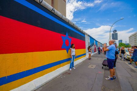 BERLIN, GERMANY - JUNE 06, 2015: Berlin wall full of graffitis and expression of people, turists taking a photo on germany flag colors with Davids star in the middle,のeditorial素材