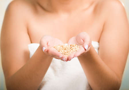 Closeup woman naked shoulders and towel wrapped around chest, pouring granola into her own hands.の写真素材