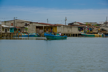 Muisne, Ecuador - March 16, 2016: Muisne town as seen from water, modest wooden houses sitting on poles waterfront pacific ocean, city buildings background and beautiful blue sky.のeditorial素材