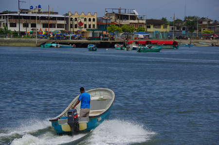 Muisne, Ecuador - March 16, 2016: Man standing inside typical fishing boat crossing water from Muisne to mainland.のeditorial素材
