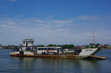 Muisne, Ecuador - March 16, 2016: Small rusty ferry on water approaching Muisne pier.のeditorial素材