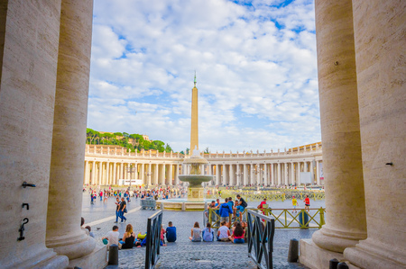 VATICAN, ITALY - JUNE 13, 2015: Great view outside Vatican Basilica, between columns the obelisk and fountaine with tourists all around.のeditorial素材
