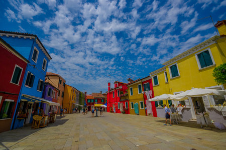 BURANO, ITALY - JUNE 14, 2015: Large perspective full color houses photo in Burano, stone path with...