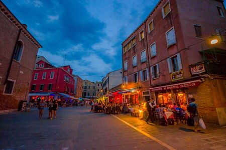 VENICE, ITALY - JUNE 18, 2015: Restaurants street in Venice, tourists looking the best place. Sky almost blue.のeditorial素材