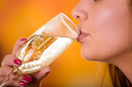 Close up of champagne cup holding by a red nails hand and beautiful lips.の写真素材