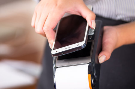 White mobile phone near a credit card machine, paper coming out, reader for this transaction.