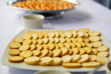 Thin crunchy toasted baguette slices stacked up on white plate.
