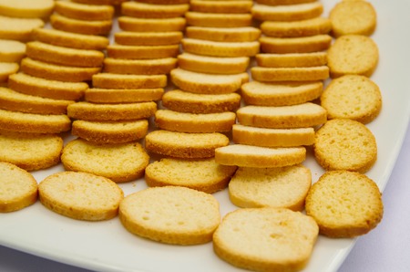 Thin crunchy toasted baguette slices stacked up on white plate.の写真素材