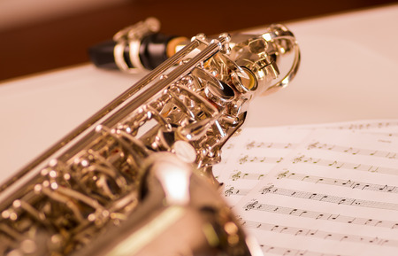 Closeup partly view of shiny saxophone lying on musical notes paper.の写真素材