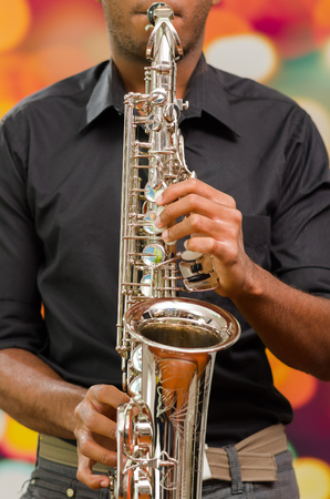 Closeup hands of man wearing dark shirt and playing saxophone.の写真素材