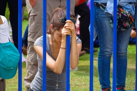 QUITO, ECUADOR - JULY 7, 2015: Young girl praying at pope Francisco mass in Ecuador, closed eyes and head down.のeditorial素材