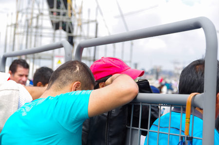 QUITO, ECUADOR - JULY 7, 2015: A young boy with blue t-shirt praying with head down, leaning against...