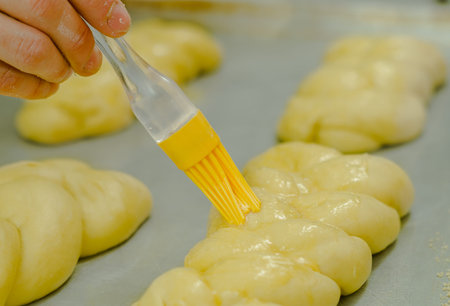 Using brush applying butter on top of beautiful kringle dough, preparing to cook in oven.