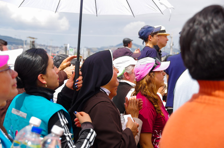 QUITO, ECUADOR - JULY 7, 2015: In the middle of thousand people a nun is praying under the sun, a police is behind her.のeditorial素材