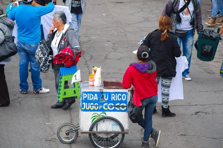 QUITO, ECUADOR - JULY 7, 2015: Woman from the back selling coconut juice, standing in the middle of the street.のeditorial素材