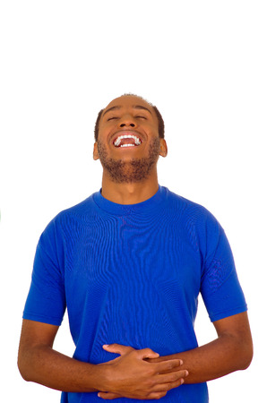 Man wearing strong blue t-shirt standing and laughing hard holding his stomach, white studio background.の写真素材