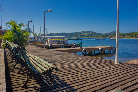 FLORIANOPOLIS, BRAZIL - MAY 08, 2016: some benches on the top of the dock close to some boats parked and a nice view of some houses at the end of the lake.のeditorial素材
