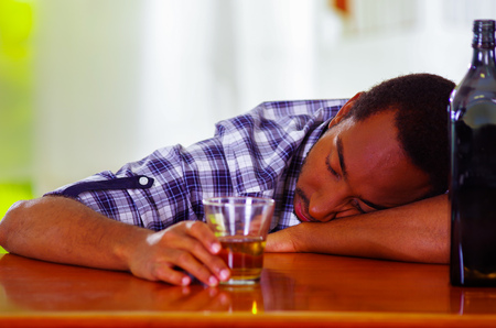 Handsome man wearing white blue shirt sitting by bar counter lying over desk drunk sleeping, alcoholic concept.の写真素材