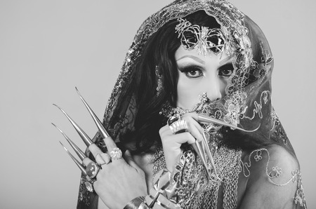 Headshot woman dressed in traditional hindu clothing, heavily decorated in gold with elegant veil, extremely long fingernails, posing artistically for camera, hindusim dancer concept, black and white edition.の写真素材