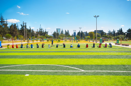 QUITO, ECUADOR - 8 AUGUST, 2016: Row of people stretching seated on football field located in inner...