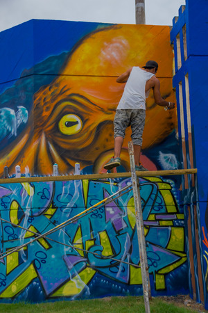 PUNTA DEL ESTE, URUGUAY - MAY 06, 2016: young man standing over a scaffold painting the final details of the grafitti.のeditorial素材